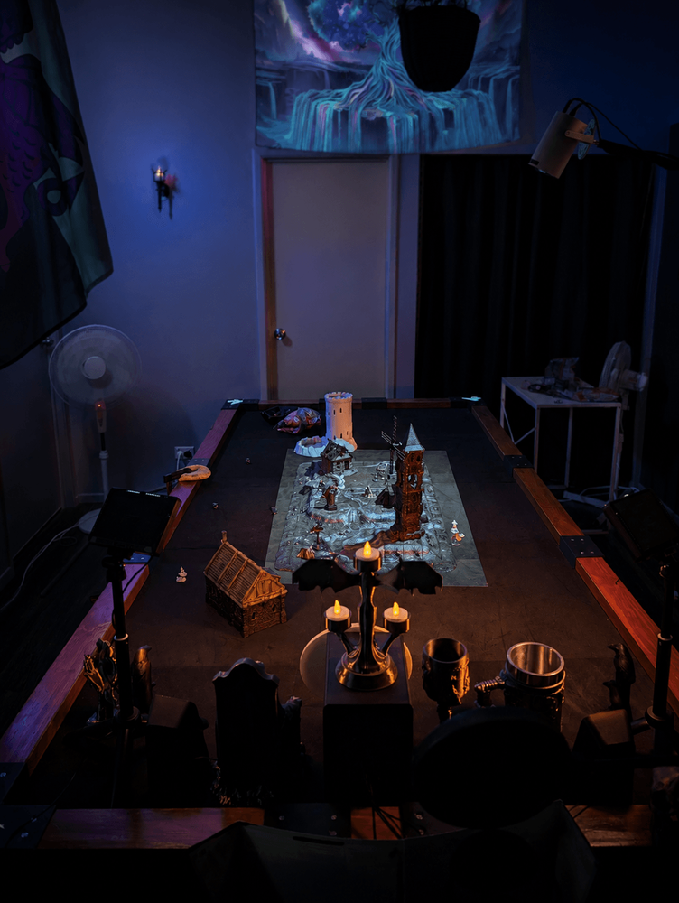 Physical miniatures and ruined terrain illuminated by blue, violet and red projected effects.